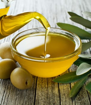 Bottle pouring virgin olive oil in a bowl close up
