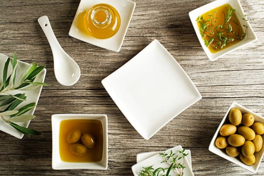 Olive oil with fresh herbs on wooden background