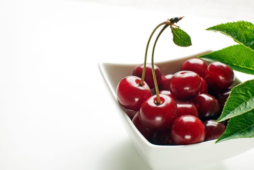 Fresh cherries in bowl on white background close up