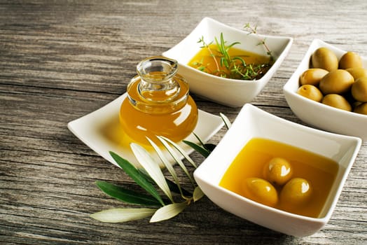 Olive oil with fresh herbs on wooden background