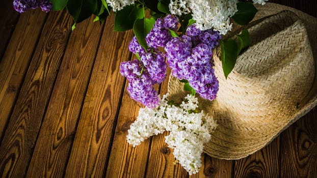 Still-life with a bouquet of lilacs and a straw hat, close-up