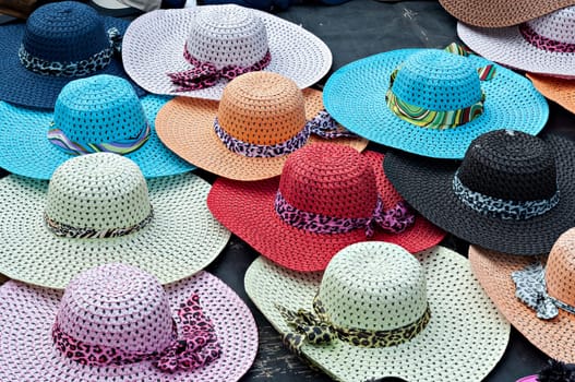 Brightly colored wide brimmed ladies straw sun hats for sale at the beachfront