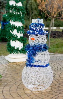 white snowman in a blue hat at the column decorated with a fir-tree, the subject Christmas and New Year