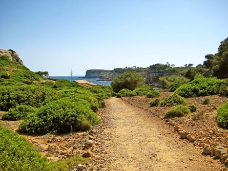 Cliff coast of Majorca in the south-east of the island between Cala s'Almonia and Calo d'Es Moro - stony path in foreground
