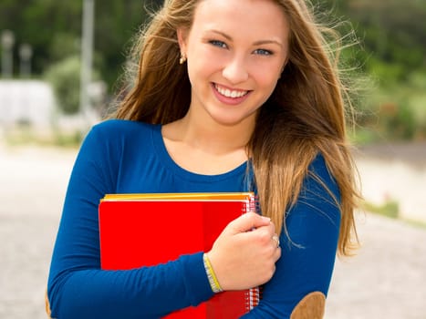 A beautiful student in the college holding a backpak and notebooks