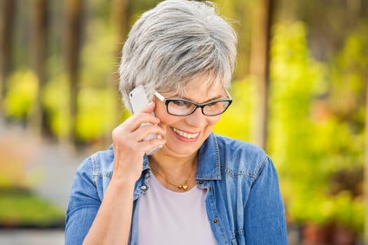 Beautiful mature woman gardening and talking at phone