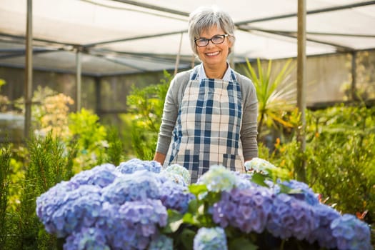 Beautiful mature woman gardening and looking at camera while smiling