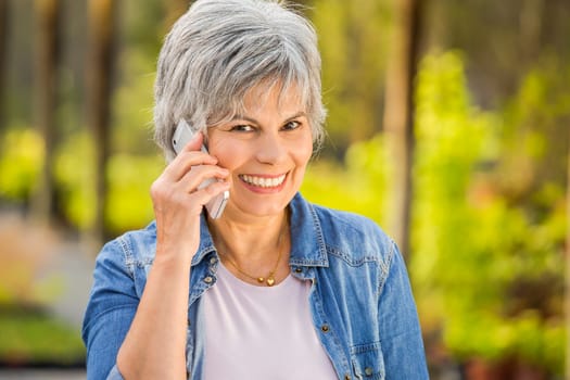 Beautiful mature woman gardening and talking at phone