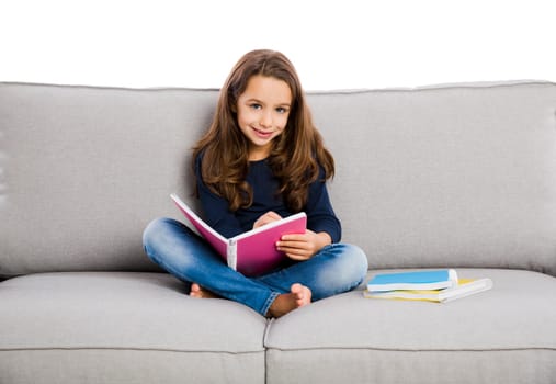 Little girl sitting on a couch and studying