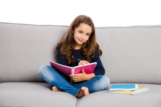 Little girl sitting on a couch and studying