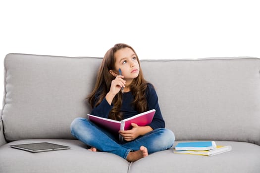 Little girl sitting on a couch and studying