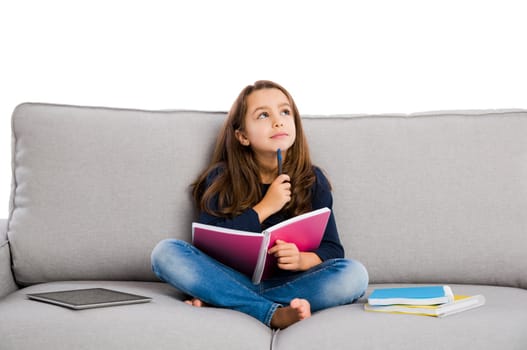 Little girl sitting on a couch and studying