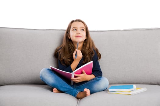 Little girl sitting on a couch and studying