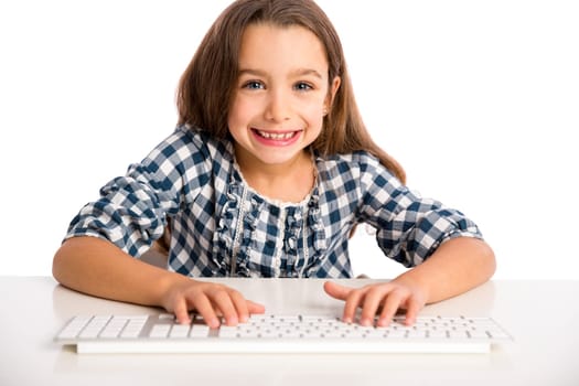 Little girl sitting on a desk and working with a computer
