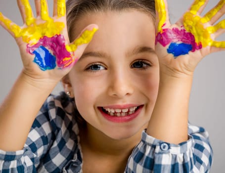 Cute smiling little girl with hands in paint