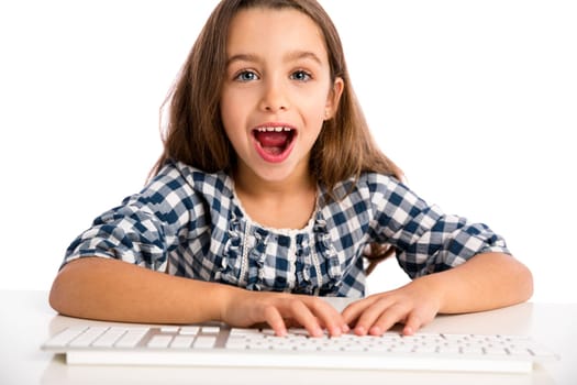 Little girl sitting on a desk and working with a computer