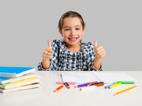 Little girl with thumbs up at school making drawings and painting