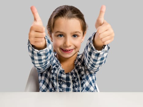 Little girl with thumbs up at school making drawings and painting