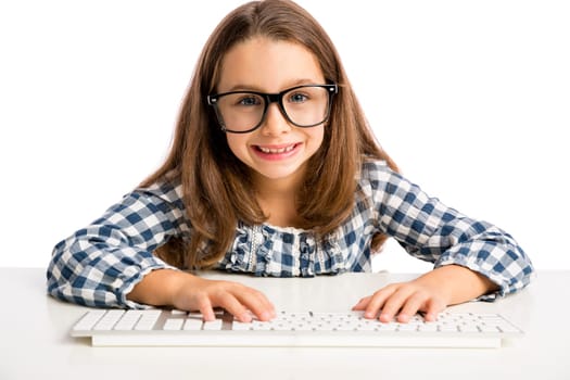 Little girl sitting on a desk and working with a computer