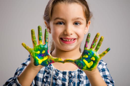 Cute smiling little girl with hands in paint