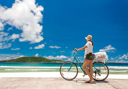 Woman on a bicycle ride along The Beach at Seychelles