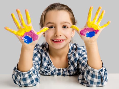 Cute smiling little girl with hands in paint