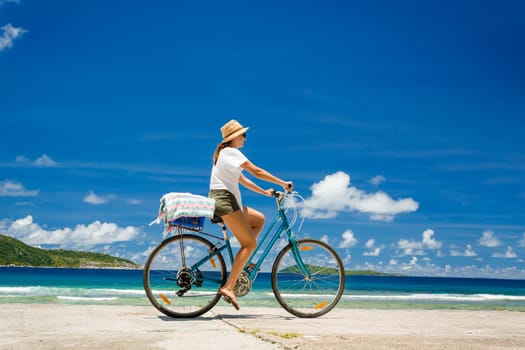 Woman on a bicycle ride along The Beach at Seychelles