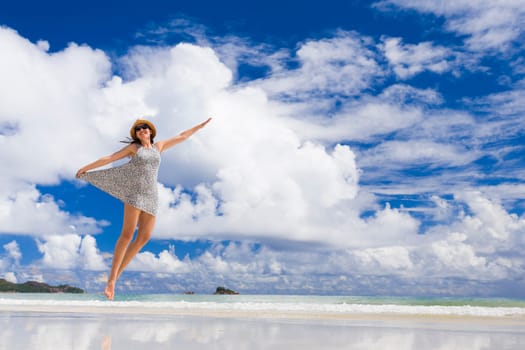 Beautiful woman jumping on the wonderful beach of Praslin, Seychelles