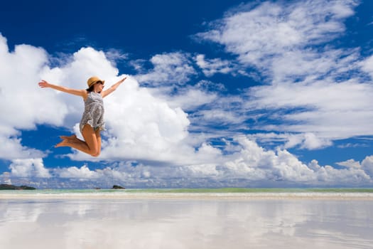 Beautiful woman jumping on the wonderful beach of Praslin, Seychelles
