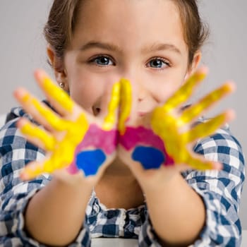 Cute smiling little girl with hands in paint
