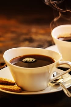 Close up on two servings of delicious hot coffee with spoon and biscuits in porcelain saucer