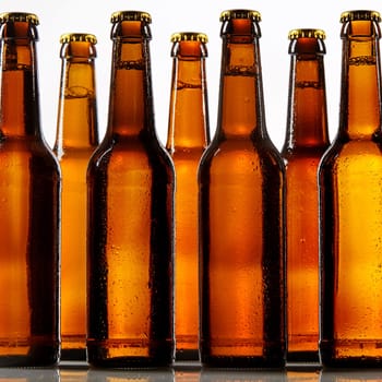 Close up view of tall beer bottles with metal caps and condensation covering each one