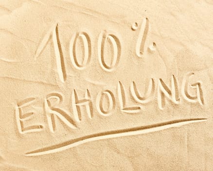 100 percent Erholung German text drawn in beach golden sand conceptual of relaxation, summer vacations and travel
