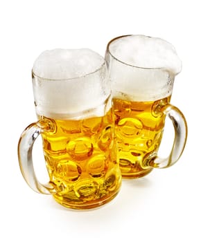 Two pint mugs of glowing golden frothy cold beer viewed high angle over white conceptual of the annual German Oktoberfest