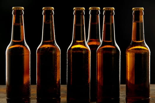 Row of ice cold unlabelled unopened brown beer bottles standing on a pub or tavern counter on a shadowy background in a branding and advertising concept for Oktoberfest
