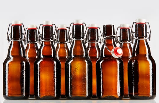 Beer packaged in clear brown unlabeled bottles two rows deep with stopper top and metal brace