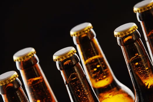 Necks of sealed beer bottles with condensation in a close up view over a black background in a tilted angle view conceptual of Oktoberfest
