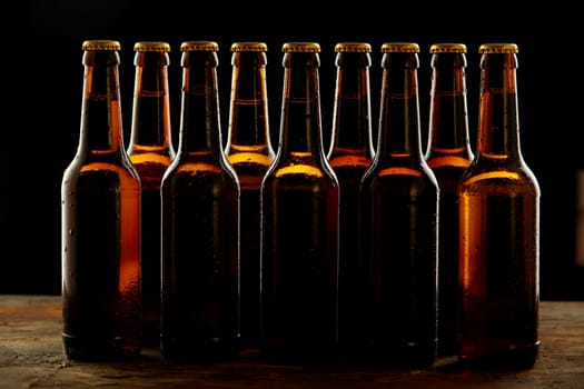 Group of sealed unlabelled brown beer bottles standing on a wooden counter in a concept of the Oktoberfest or for branding and advertising