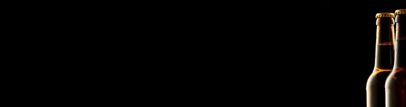 Wide panoramic Oktoberfest banner with two sealed chilled beer bottles on the right side as a border and plenty of copy space on black