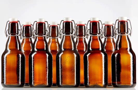 Two rows of nine tall blank glass bottles with copy space used for beer or other commercial beverages over gray background