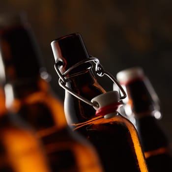 Open bottle of beer with stopper in a close up selective focus tilted view in square format in a dark environment conceptual of Oktoberfest