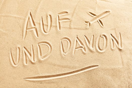 Auf und Davon German text with sketched airplane on tropical beach sand conceptual or spring or summer vacations and flying by air to your holiday destination