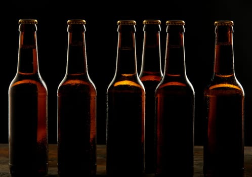 Branding and marketing concept for beer with a line of unopened unlabelled full blank brown bottles on a dark shadowy background conceptual of Oktoberfest or nightlife