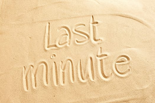 Conceptual image of Last minute holiday deals for a tropical summer vacation with the text handwritten on golden beach sand