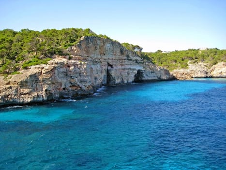 Coastline with turquoise water, mountain and caves - ocean / mediterranean sea in front