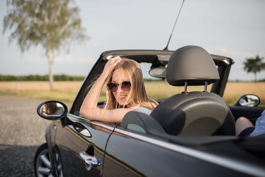 Young woman looks out of a convertible