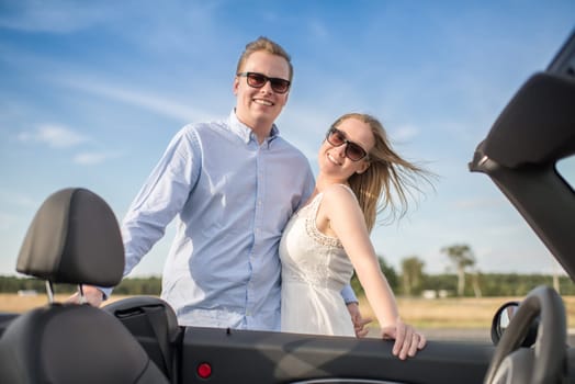 Couple hugs the convertible and is happy