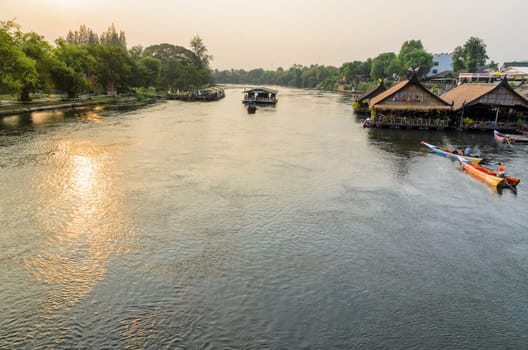 High angle view from bridge, beautiful landscape of Kwai Yai River at sunset and lifestyle of people on the waterfront in Kanchanaburi Province, Thailand