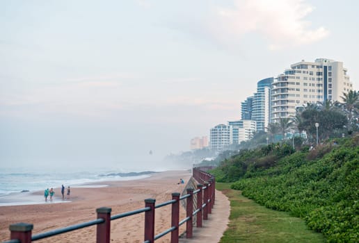 DURBAN, SOUTH AFRICA - MAY 24, 2016: Locals and tourists on the beach and walking along the promenade in Umhlanga Rocks at Sunset