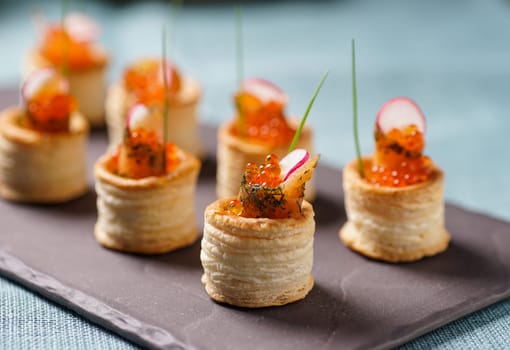 Delicious appetizers with graved salmon and golden caviar served in puff pastry towers